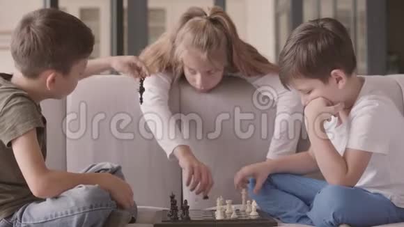 孩子们坐在家里的沙发上下棋兄弟姐妹花时间在室内幸福的家庭无忧无虑的童年视频的预览图