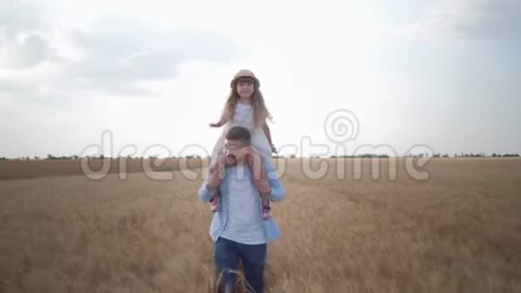 年轻开朗的父亲带着他可爱的小女儿在肩膀上奔跑摇动着她的父亲快乐的画像视频的预览图