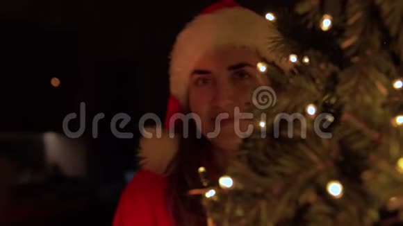 戴着萨纳帽子的女人在家中的圣诞树上视频的预览图