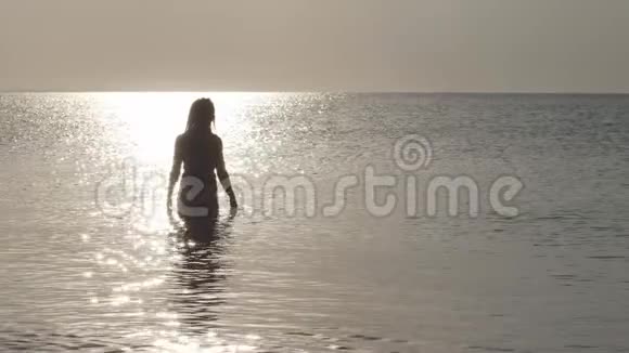 穿着比基尼的女人站在阳光下的马路中间海水中温柔的波浪摇曳着闪耀着光芒视频的预览图