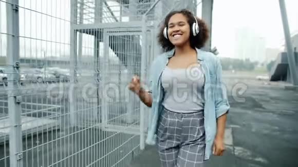 戴着耳机在户外跳舞的非裔美国女孩慢动作视频的预览图