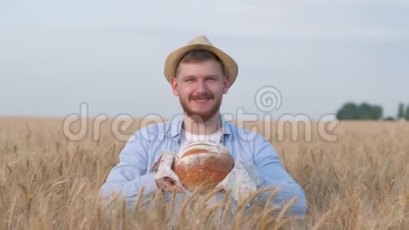 一幅成功的农学家的画像年轻人给你刚烤好的面包在麦田里对着镜头微笑视频的预览图