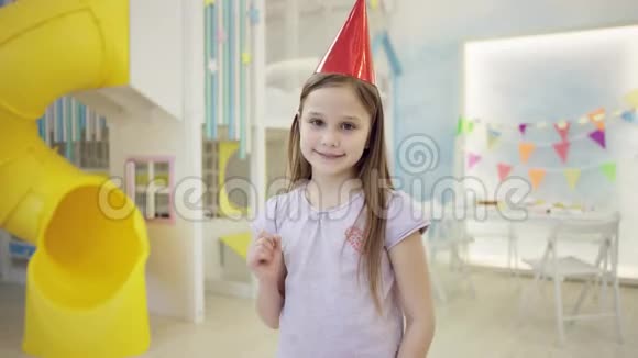 戴着生日帽的快乐女孩用拇指手指对着镜头视频的预览图