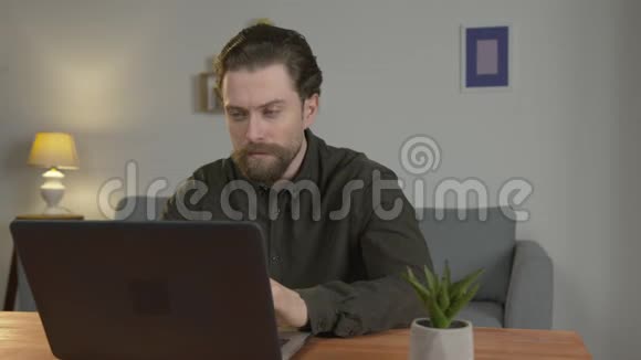 一个男人在笔记本电脑上工作打印坐在桌子上在家工作呆在家里挑战视频的预览图