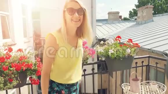 阳光明媚的浪漫阳台上戴着太阳镜的快乐微笑迷人的女人视频的预览图