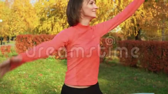 在秋季公园的舞蹈课上跳舞的女运动员舞女在多彩公园的户外舞蹈课培训视频的预览图