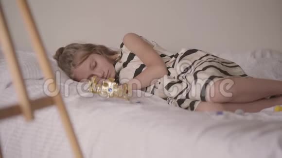 可爱的睡眠平静的白种人女孩躺在他舒适的床上孩子玩游戏后休息免费视频的预览图