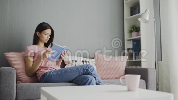 女人在家里沙发上看书和表演视频的预览图