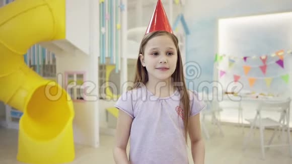 戴着锥帽的快乐小女孩在镜头前拿到一个大礼物盒视频的预览图