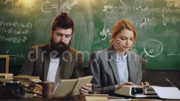 年轻聪明的人正在努力工作学校班上的男人和女人男人看书女人用打字机打印男性视频的预览图