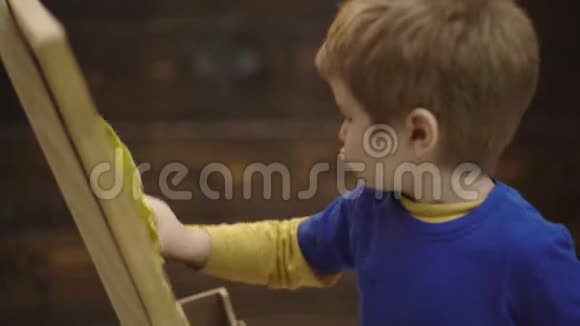 孩子在木制背景上擦黑板特写孩子的工作儿童男孩集中脸擦桌子视频的预览图