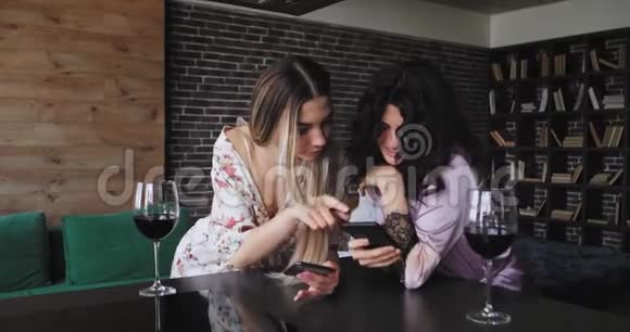 在一个现代化的公寓里两位女士非常有魅力一边喝着几杯一边用智能手机发短信视频的预览图