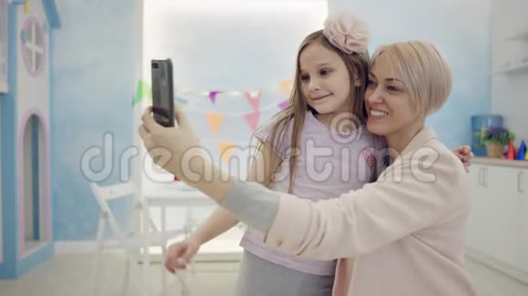 小女孩在镜头前用智能手机帮妈妈自拍视频的预览图
