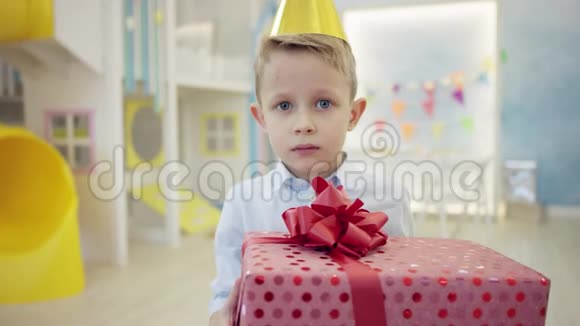 戴着锥帽的愤怒小男孩在镜头前检查他的生日礼物视频的预览图