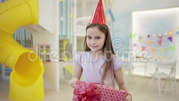戴着生日帽的迷人女孩拿着她的大礼物盒在镜头前视频的预览图