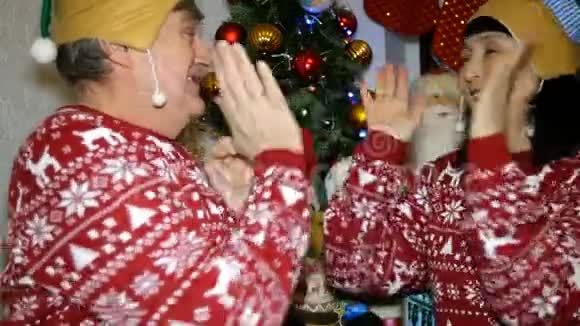 家庭圣诞节两个年长的成年人男人和女人穿着圣诞毛衣和帽子玩愚弄周围和视频的预览图