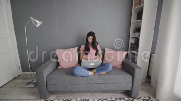 一个漂亮的女人在沙发上用电脑工作视频的预览图