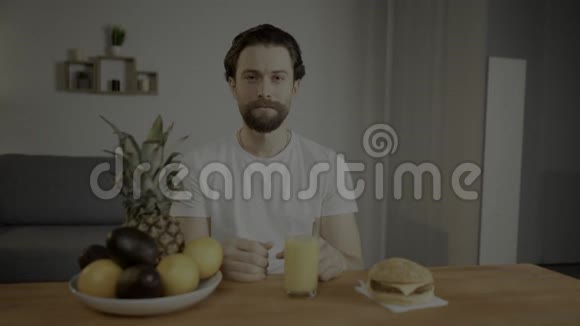 年轻人坐在一张桌子上在一盘水果果汁和汉堡包上一个人正在枯萎有用的产品人类发展报告视频视频的预览图