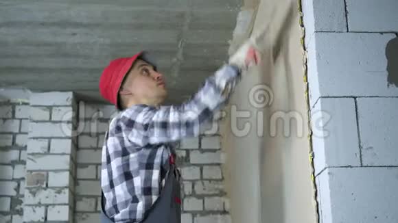 青年建筑工人在房屋建筑工地平整抹灰墙视频的预览图