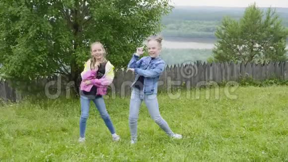 在森林和河流景观的绿色草地上翩翩起舞的嬉戏少年女孩无忧无虑的少女们玩得开心视频的预览图