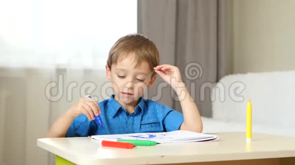 一个小男孩坐在房间里的桌子旁画画想象着一个家庭孩子画画情绪快乐视频的预览图