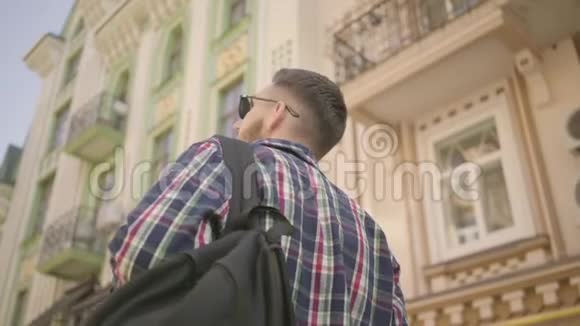 在旧欧洲城市的街道上年轻的积极男子背着背包年轻的游客视频的预览图