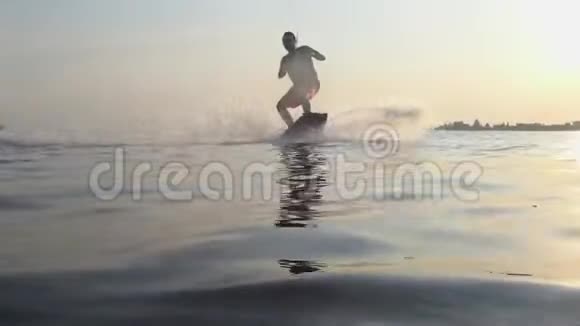 水上运动唤醒者男子骑在摩托艇后面的船在河上并在相机镜头的背景上飞溅视频的预览图