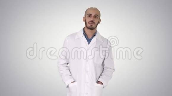 阿拉伯英俊的医生穿着他的制服走路双手在口袋里的梯度背景视频的预览图