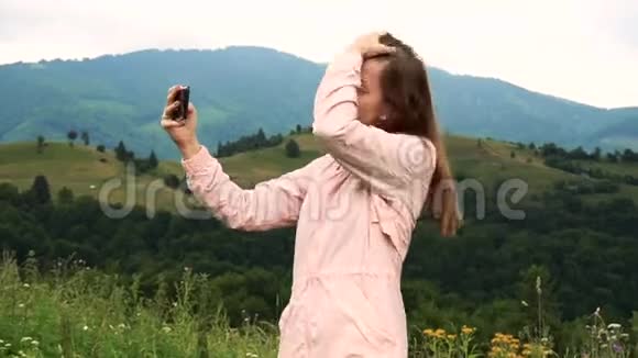 女人在智能手机上拍摄自拍照片可以看到群山视频的预览图