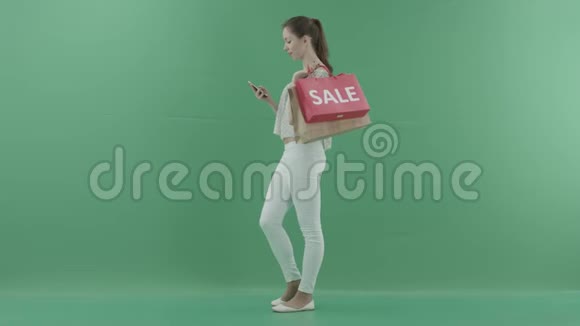 有魅力的女人站在个人资料上在智能手机上浏览互联网在绿色屏幕上看某人视频的预览图