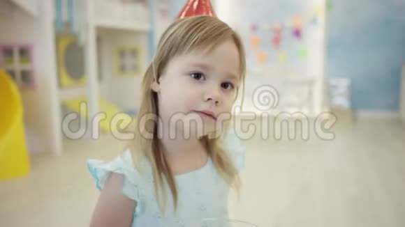 可爱的小女孩正在镜头前戴着锥帽吃糖果视频的预览图