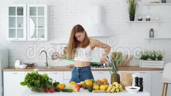 年轻的运动女孩测量她的腰部靠近一张有健康食物的桌子视频的预览图