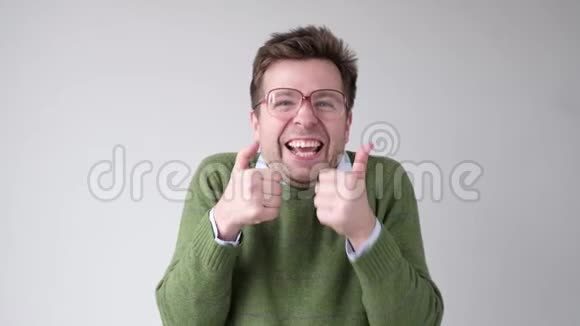 穿绿色毛衣的快乐男人竖起大拇指视频的预览图