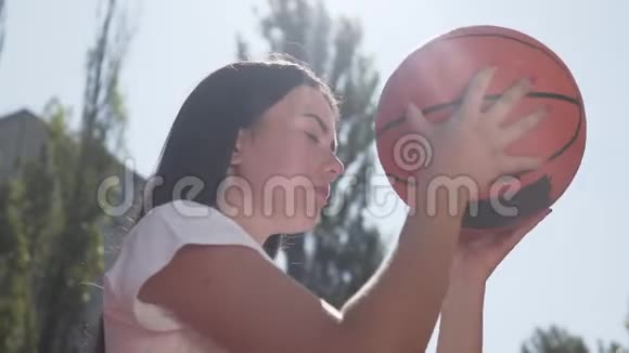 一幅漂亮的黑发女人在投掷前集中注意力拿着球靠近她的头体育概念视频的预览图
