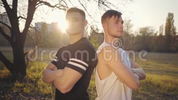 两个年轻的白人健美运动员站在阳光下看着摄像机英俊强壮的运动员花时间视频的预览图