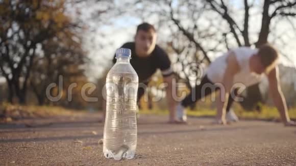 两个高加索青年运动员在日落时在秋天的公园里奋力前行运动男孩在户外训练重点放在视频的预览图