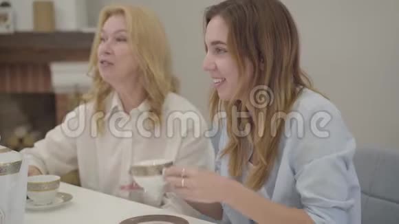 成熟的高加索女人在后台说话年轻漂亮的欧洲女孩在喝茶或咖啡视频的预览图