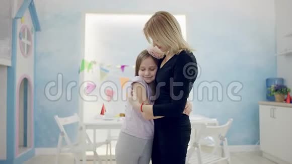 快乐的成年女人和小女孩在房间里的镜头前拥抱着对方视频的预览图