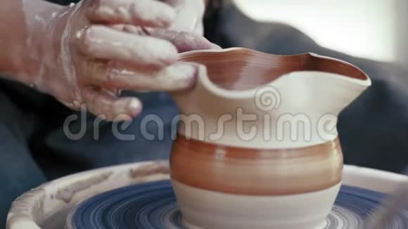 特写镜头陶工的手在陶工的圆圈上贴着泥壶视频的预览图