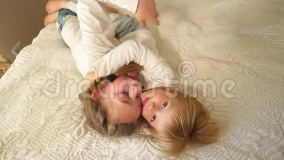 弟弟妹妹抱在床上快乐的家庭男孩和女孩手持视频的预览图