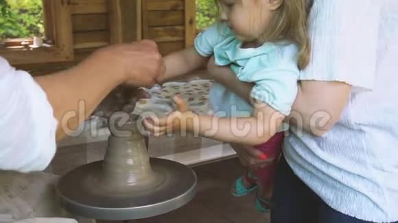 手艺人帮助女孩在陶器上制作杯子视频的预览图