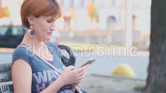 女士使用智能手机放松在长凳上的街道黄色4K植物园中的年轻千禧妇女视频的预览图