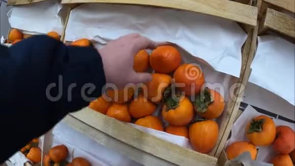 男人在食品市场上选择柿子有机食品农业视频的预览图