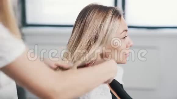 在头发护理程序前应将发型师的双手合拢梳理女性湿发视频的预览图