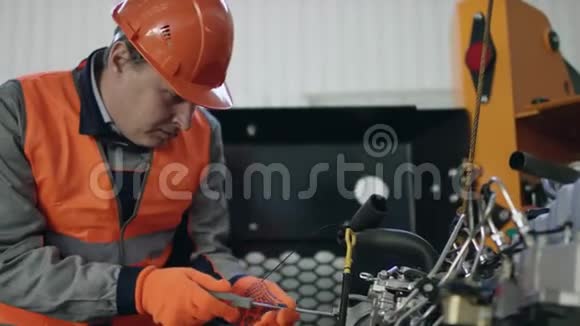 一名工人戴着头盔穿着工作服修理汽车发动机的小故障用流动摄像机扭曲细节视频的预览图