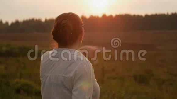 日落时分站在田野里的女孩在刷牙视频的预览图
