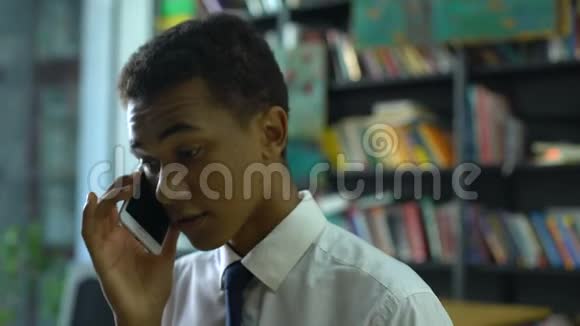 智能男性高中生会说话智能手机在学院图书馆通讯视频的预览图
