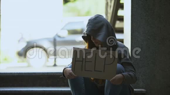 穿着连帽衫的伤心少女在街上举着帮助标志男人伸出援手视频的预览图