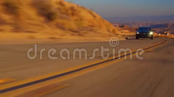 黑色汽车奥迪A6与驾驶在山区道路上日落和山脉背景下的微光拍摄在山上的公路视频的预览图