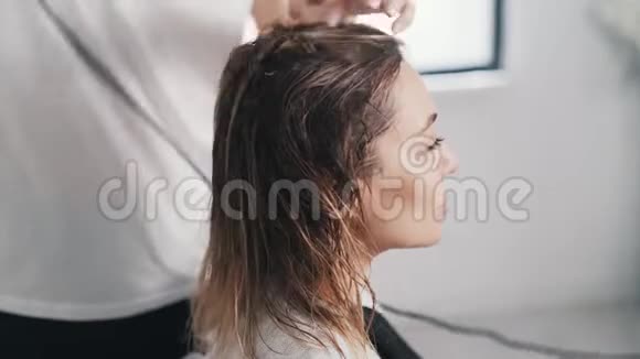 关闭理发师用吹风机擦干女性湿发客户使用手机视频的预览图